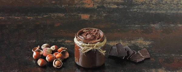 Banner. Chocolate nut paste in a jar. Hazelnut, dark chocolate. The concept of cooking chocolate and nut paste.