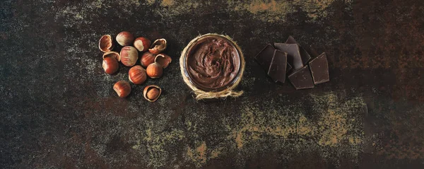 Banner. Chocolate nut paste in a jar. Hazelnut, dark chocolate. The concept of cooking chocolate and nut paste.