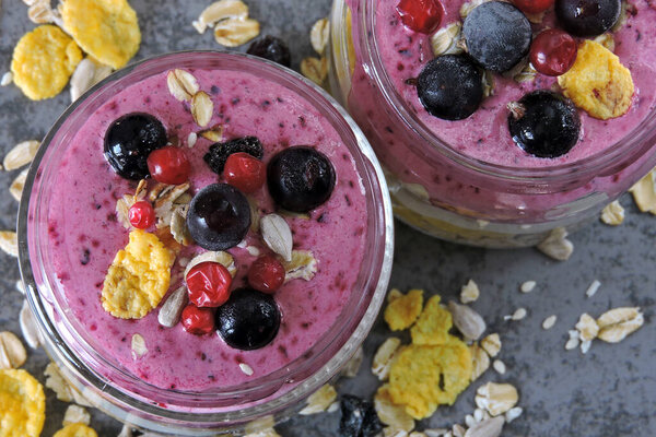 Berry yogurt with granola, flakes and berries. Jars with healthy bright smoothies and yogurt. Purple Smoothie Keto breakfast or dessert. Keto diet.