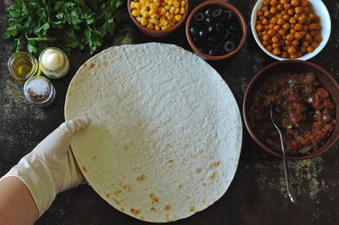 Vegan shawarma pişiriyorum. Elleri mutfak eldivenlerine sarın ve pide ekmeğine sarın. Orta Doğu mutfağı.