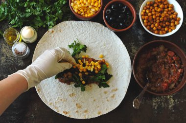 Vegan shawarma pişiriyorum. Elleri mutfak eldivenlerine sarın ve pide ekmeğine sarın. Orta Doğu mutfağı.