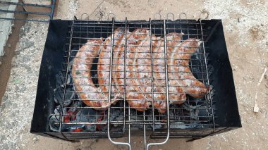 Seçici odaklanma. Izgarada iştah açıcı sosisler. Izgara sosis pişiriyorum.