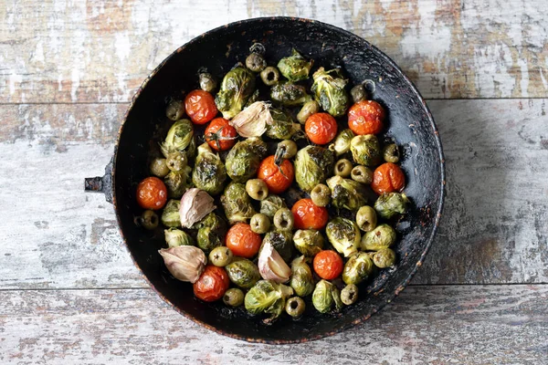 Baked Brussels sprouts in a pan with cherry tomatoes, garlic and olives. Healthy food. Vegan diet. Vegetable pan.