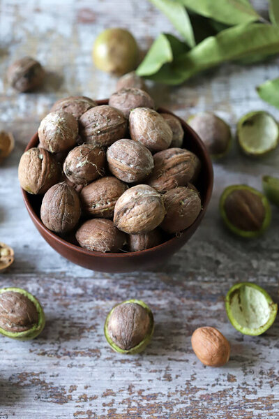 Freshly walnuts in a bowl. Harvest walnuts. Walnuts peeled from green shells. The leaves of the walnut tree.