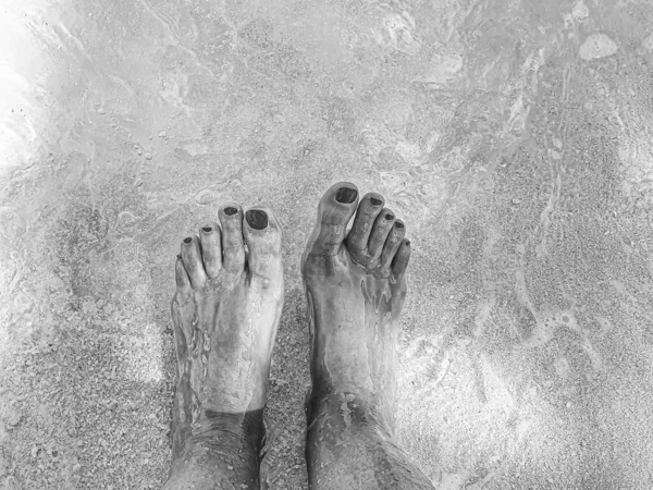 Pies con uñas de color de esmalte rojo en el mar cristalino o — Foto de Stock