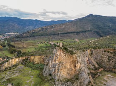 Küçük bir tepenin tepesindeki antik bir kulenin havadan görünüşü.