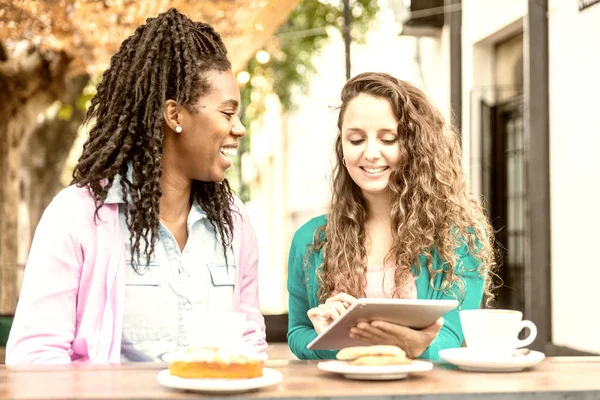 Two girlfriends watch the tablet at the Coffee Bakery shop