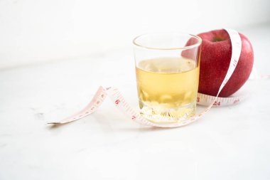 Elma ve elma suyu beyaz mermer yüzeyde ölçü bandıyla sarılmış. Meyve ve besin ve diyet gıdası kavramı.