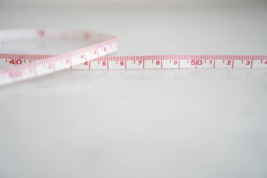 Beyaz arka planda mezura. Diyet kilo kaybı ve ölçüm kavramı.