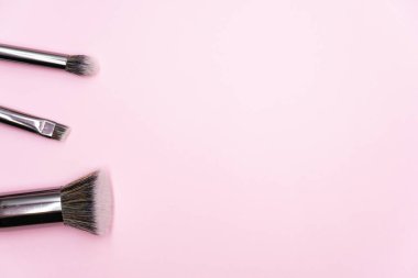 Pembe arka planda gümüş saplı profesyonel makyaj fırçaları ve fotokopi alanı. Güzellik ve yüz estetiği kavramı