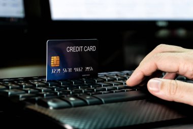 Klavyede kredi kartı ve monitörle el ele. Teknoloji ve e-ticaret kavramı.