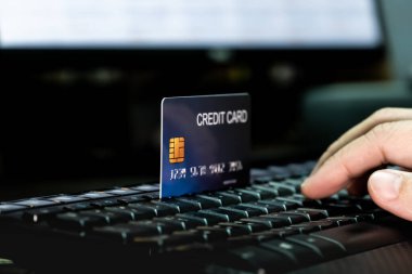 Klavyede kredi kartı ve monitörle el ele. Teknoloji ve e-ticaret kavramı.