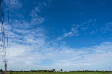 Yeşil alanlar ve beyaz bulutlarla mavi gökyüzü arkaplanı.