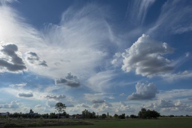 Yeşil alanlar ve beyaz bulutlarla mavi gökyüzü arkaplanı.