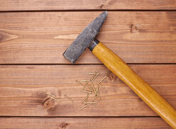 Großer Hammer mit einem Haufen Metallnägel auf der Holzoberfläche — Stockfoto