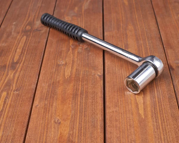 Socket metal wrench with black handle on wooden surface Royalty Free Stock Images