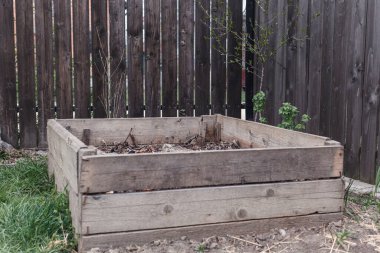 Ahşap çitlerin arkasında yaprakları olan ahşap gübre kutusu.