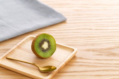 Tahta bir arka planda tahta bir tabakta kivi meyvesi aç.