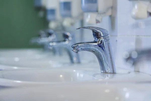 Viele Wasserhähne, weißes Waschbecken — Stockfoto