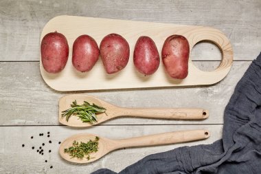 Tahta kaşıkla kimyon ve biberiye, patates, soğan, sarımsak ahşap arka plan üzerinde. Üstten Görünüm.