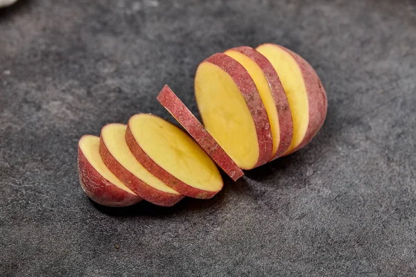 Red potato on black wood table in kitchen. Preperation for cooking. — Stock Photo, Image
