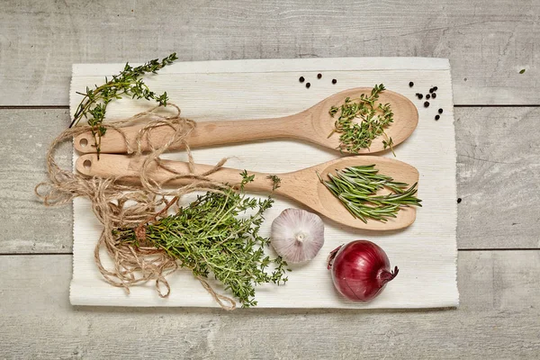 Cucchiaio di legno con cumino e rosmarino, cipolla, aglio su fondo di legno. Vista dall'alto . — Foto Stock