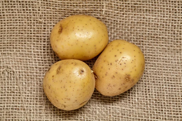 Potato on black wood table in kitchen. Preperation for cooking. — Stock Photo, Image