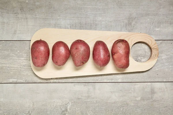 Patata rossa su tavolo in legno nero in cucina. Predisposizione per la cottura . Foto Stock