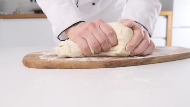 Male hands kneading dough in flour on a table and wooden board. Close up. — Stock Video