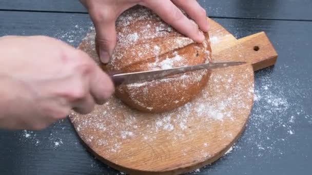 Erkek ellerinin siyah bir tahta üzerinde ekmek dilimleri kesmesi. — Stok video