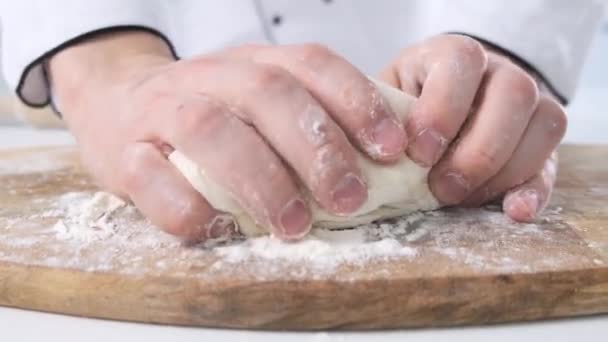 Male hands kneading dough in flour on a table and wooden board. Close up. — Stock Video