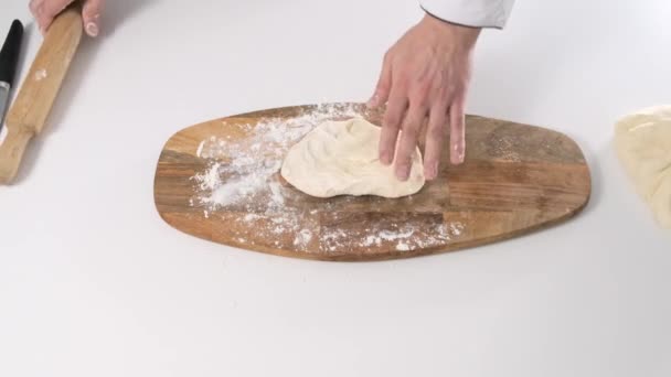 Man rolls dough with rolling pin on wooden chopping board. Close up. — Stock Video