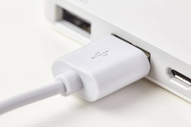 Beyaz Usb kablosu arka planda izole edilmiş bir dizüstü bilgisayara. Kapat..