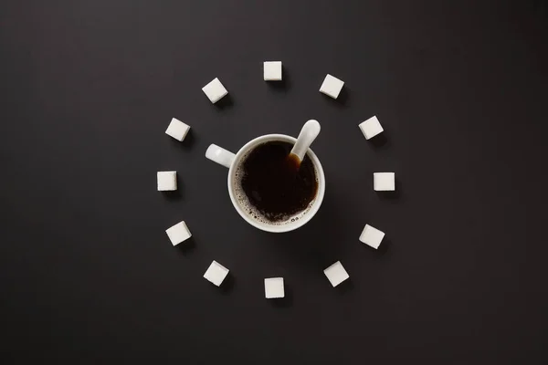 Xícara de açúcar de café como um relógio em um fundo preto. Vista superior . — Fotografia de Stock