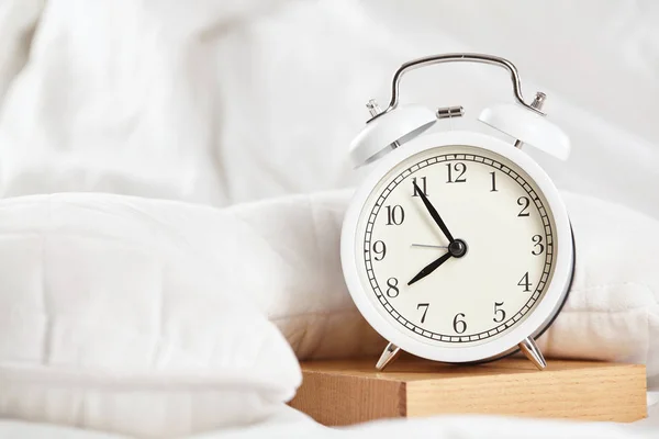 Reloj despertador en la cama blanca. De cerca. . —  Fotos de Stock