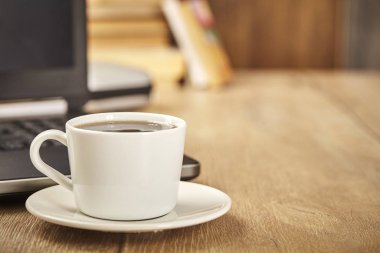 Wood office desk table with laptop and cup of coffee. Copy space. Close up.