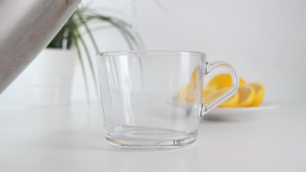 Pouring hot tea into glass cup on white kitchen table. Close up. — Stock Video