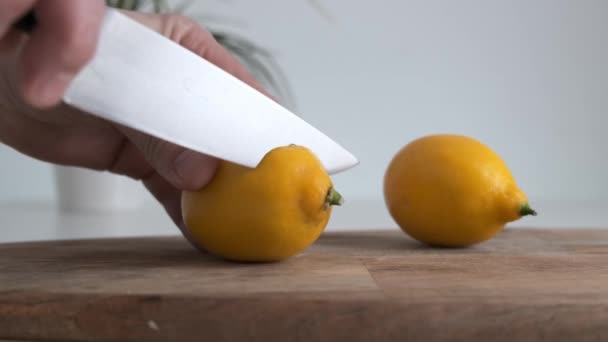 Corte a mano un limón en la tabla de cortar de madera en la cocina. De cerca. . — Vídeos de Stock