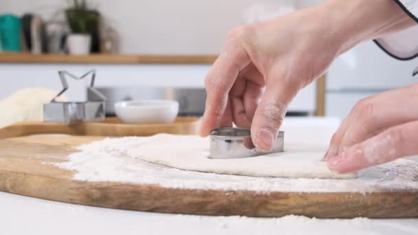 Female hands cutting out shapes from rolled dough with heart cutters on white table. Close up. — 비디오