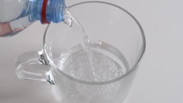 Öntsön egy átlátszó pohár hideg vizet palack fehér alapon. Közelről.. — Stock videók