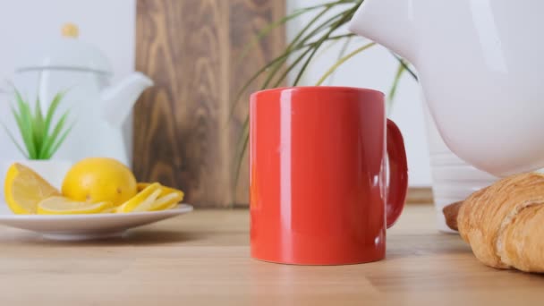 Горячий кофе наливают в красную чашку на дубовый стол. Закрыть . — стоковое видео