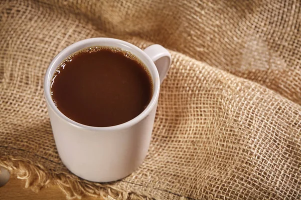 Taza de café sobre tabla de madera y fondo de saco. De cerca. . — Foto de Stock