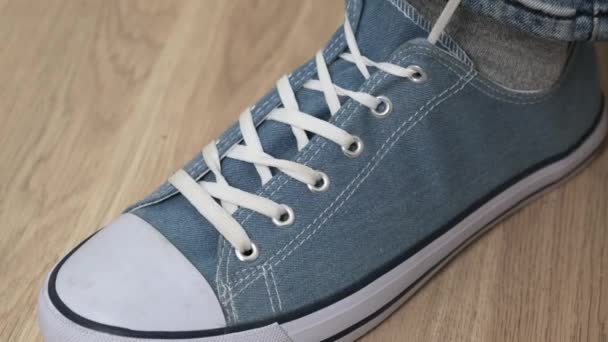 Human Hands lace up blue sneakers on wooden background. Close up. — Stock Video