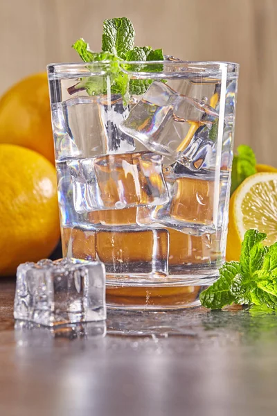 Water with lemon, mint and ice on wooden table. Close up. — Stock Photo, Image