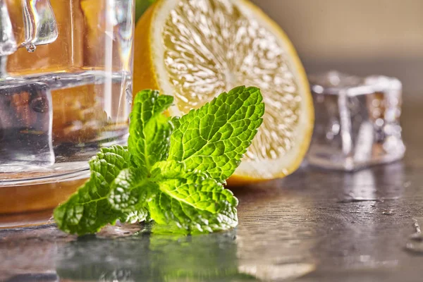 Wasser mit Zitrone, Minze und Eis auf einem Holztisch. Nahaufnahme. — Stockfoto