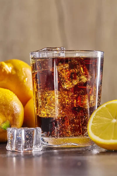 Cocktail with cola on a wooden table, ice, lemon. Close up. — Stock Photo, Image