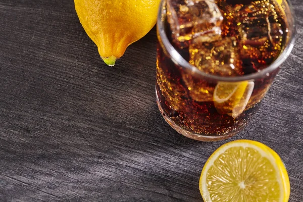 Cocktail with cola on a wooden table, ice, lemon. Close up. — Stock Photo, Image