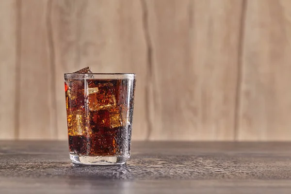 Transparent glass of cola with ice cubes on wood table. Close up. — Stock Photo, Image