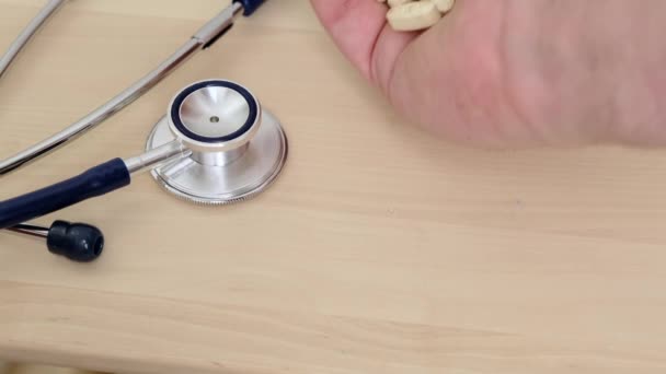 Medicin piller i handen och stetoskop i bakgrunden. Sjukvårdskoncept. Närbild. — Stockvideo