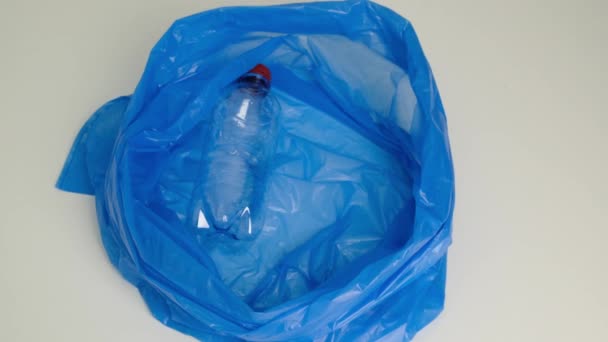 Eine Plastikflasche in einen Müllsack legen. Nahaufnahme. — Stockvideo